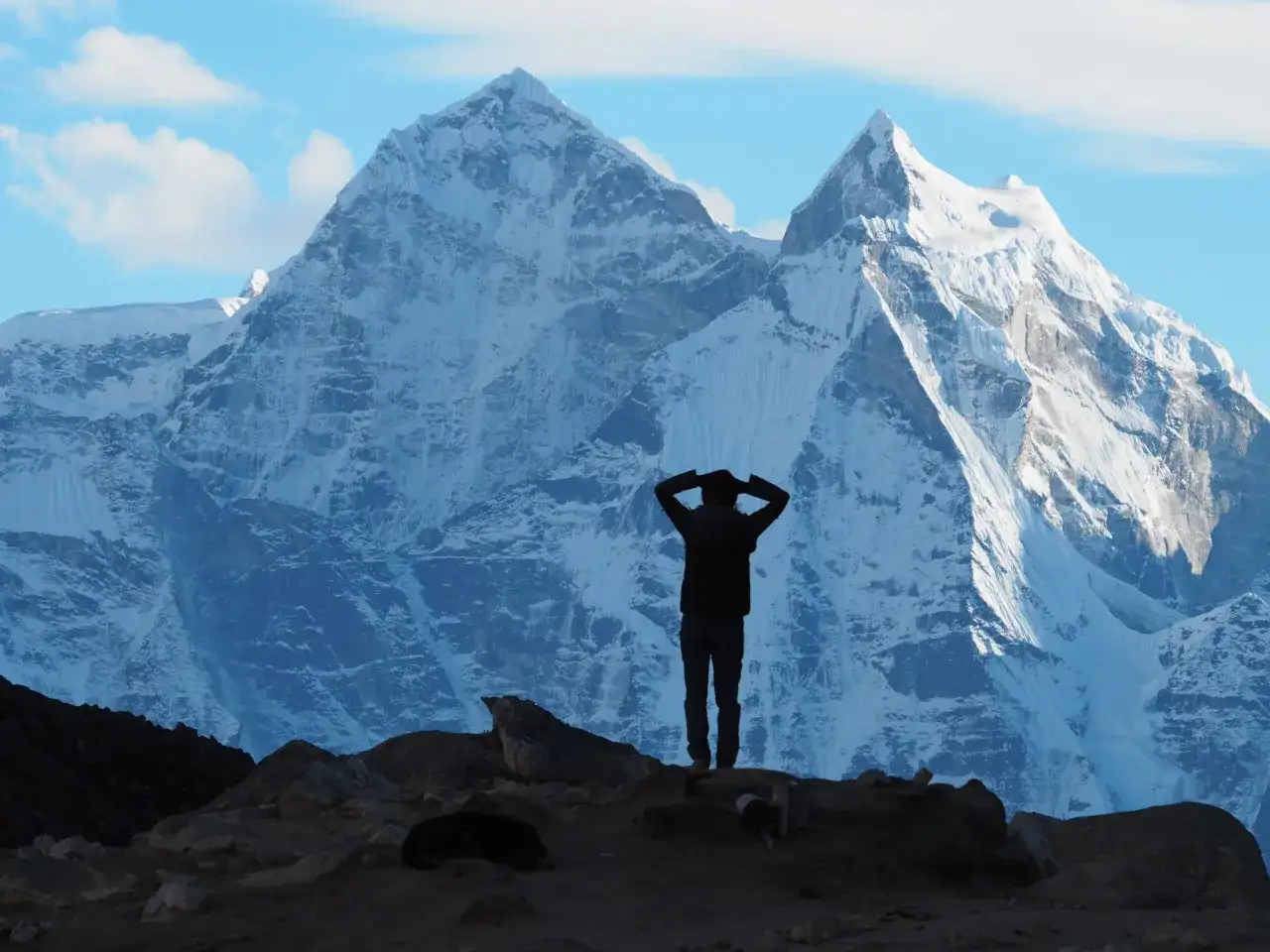 Sylwetka człowieka na tle ośnieżonych gór. Czy to początek choroby wysokościowej, czy tylko chwila zadumy przed dalszą wspinaczką?
