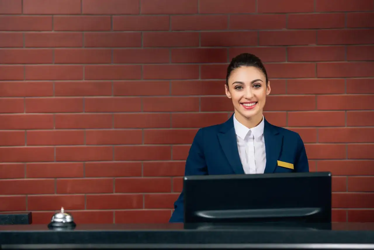Uśmiechnięta recepcjonistka w hotelu, gotowa pomóc gościom. Jej angielski jest płynny, a uśmiech serdeczny.