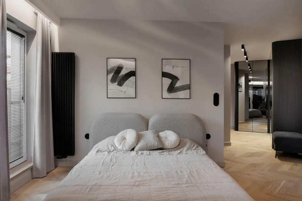 Nowoczesna sypialnia z łóżkiem i dwoma obrazami. Dyskretne gniazdka pokazują, jak rozmieścić kontakty w sypialni, by były estetyczne i funkcjonalne.