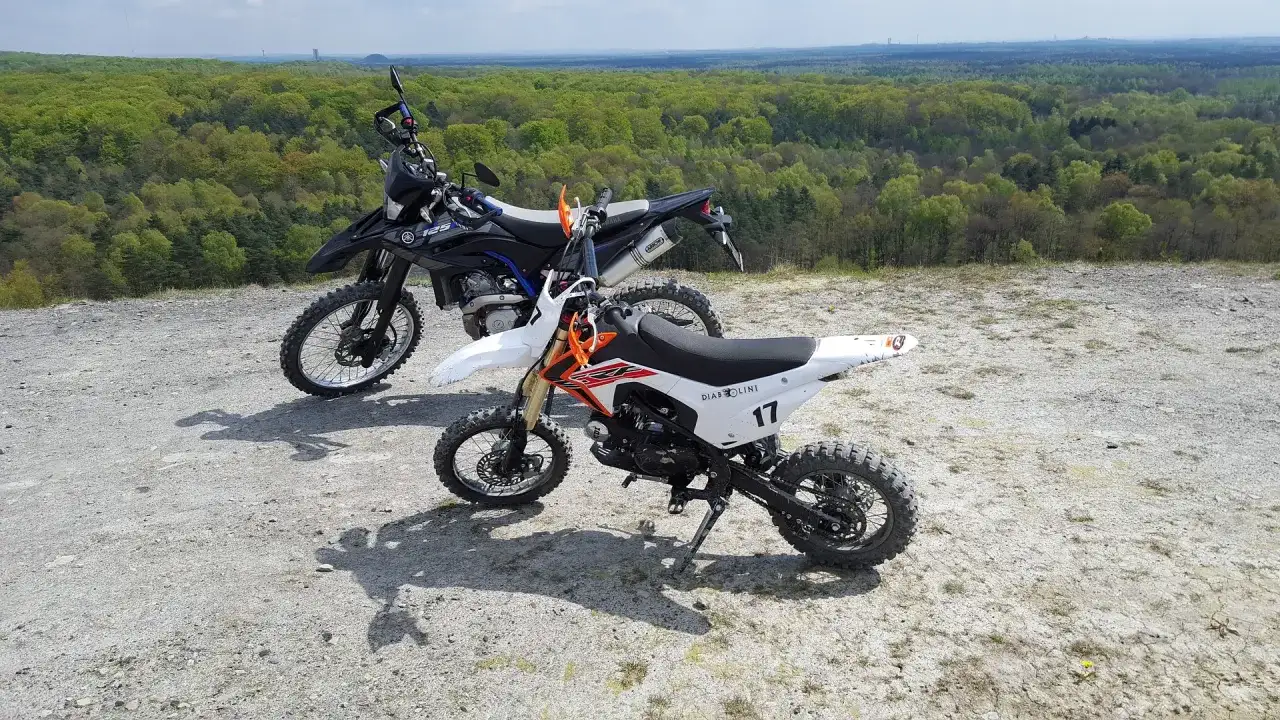 Dwa motocykle crossowe na tle lasu. Czy crossem można jeździć po ulicy? Te maszyny są stworzone do terenu.