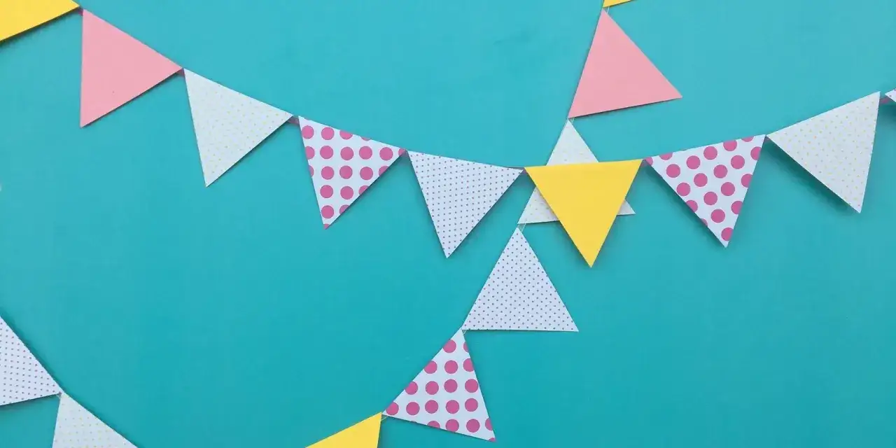 Kolorowa girlanda z trójkątnych chorągiewek w kropki i jednolite, tworzy radosną dekorację.