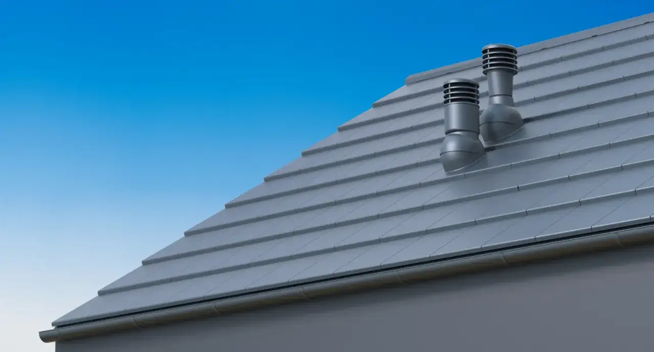 Dwa kominki wentylacyjne na szarym dachu. Pokazują, jak połączyć kominek wentylacyjny z kominem, zapewniając prawidłową cyrkulację powietrza.