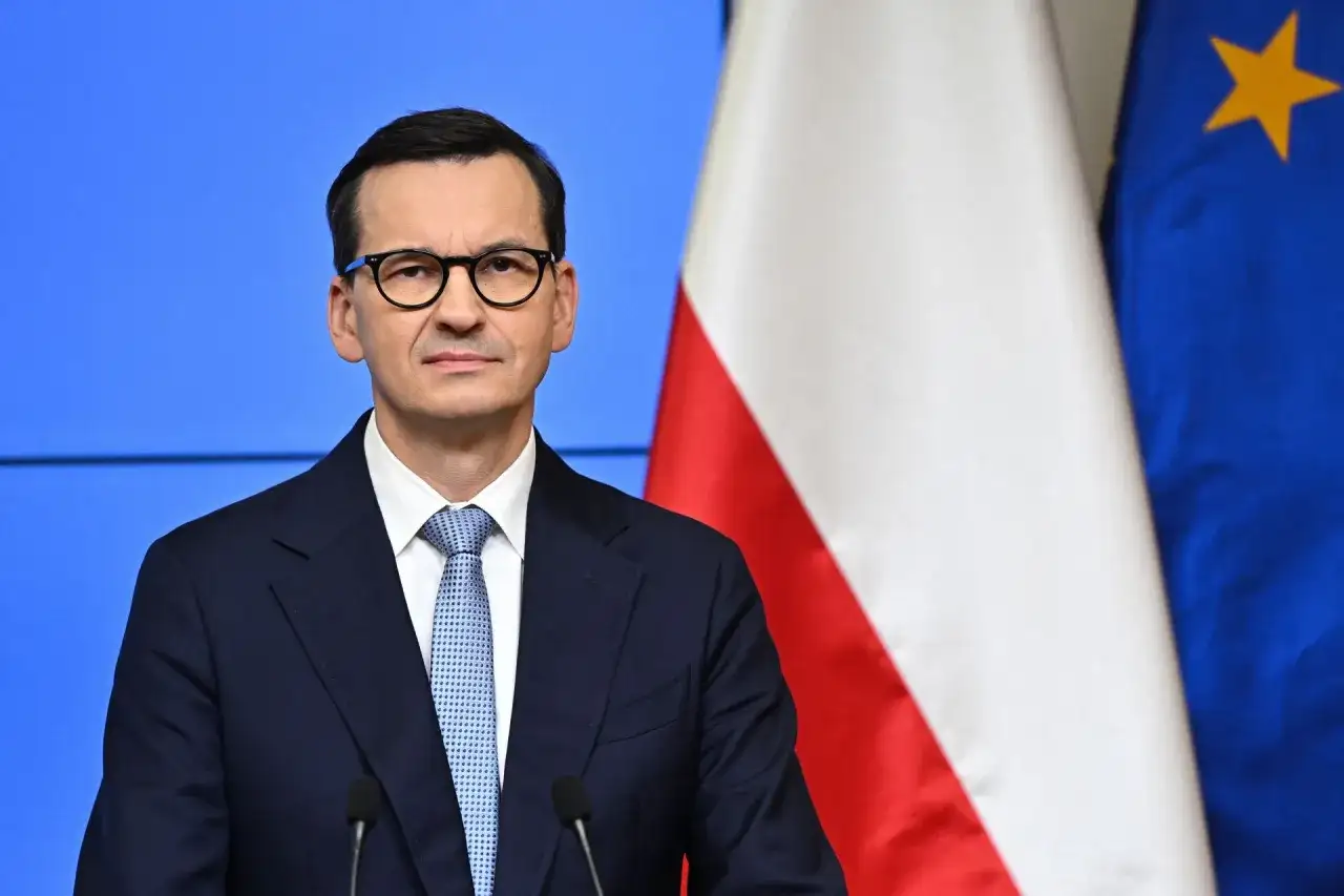 Mateusz Morawiecki w okularach, obok flagi Polski i UE. Jego rządzenie trwa od 2017 roku, kiedy to zastąpił Beatę Szydło.
