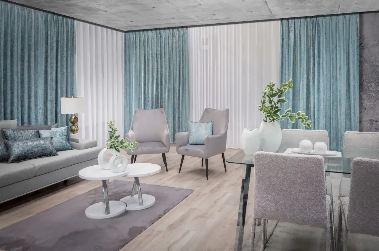 Eleganckie firany w salonie tworzą przytulną atmosferę. Szare fotele i kanapa dopełniają nowoczesny wystrój.