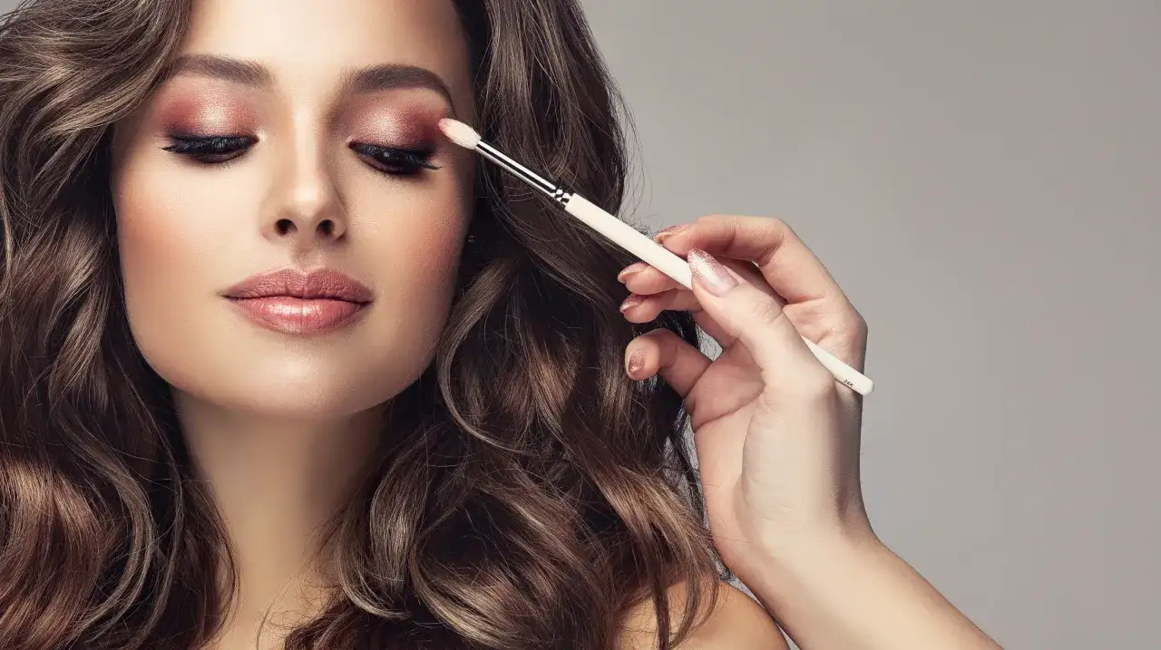 Kobieta z makijażem oczu w odcieniach różu i brązu, aplikowany pędzelkiem.
