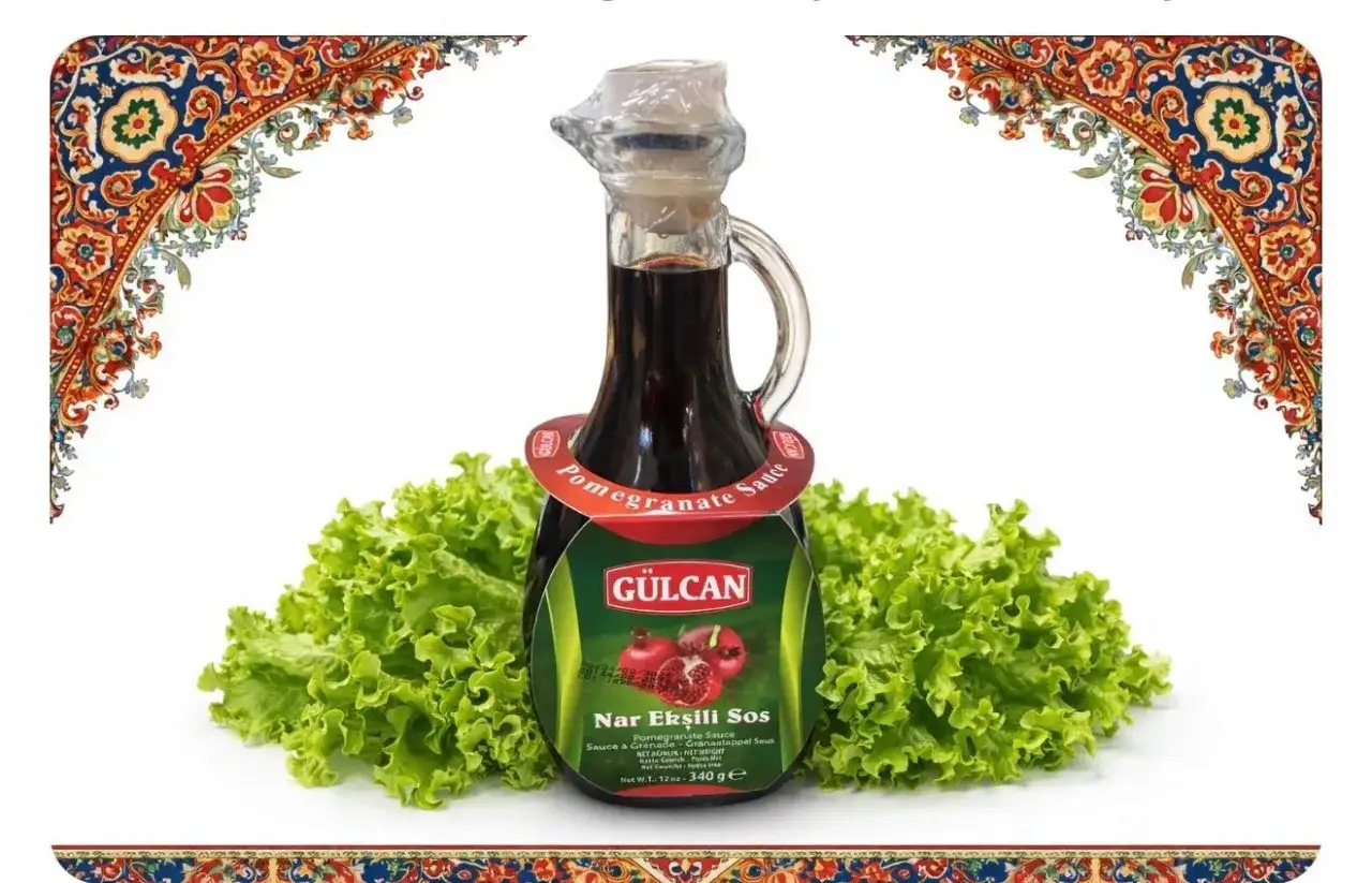 Butelka sosu z granatu Nar Ekşili Sos na tle sałaty, ozdobiona orientalnymi wzorami.