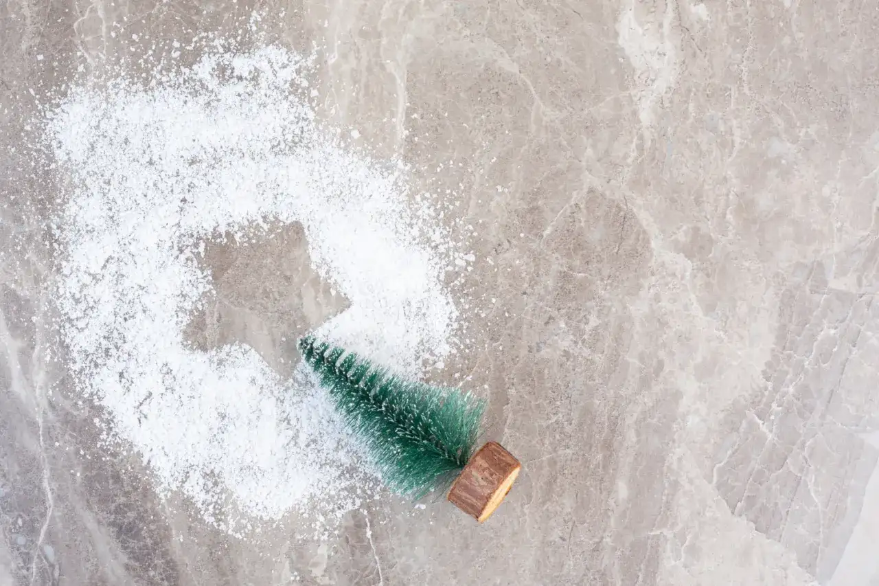 Mała choinka w sztucznym śniegu na marmurowym tle.