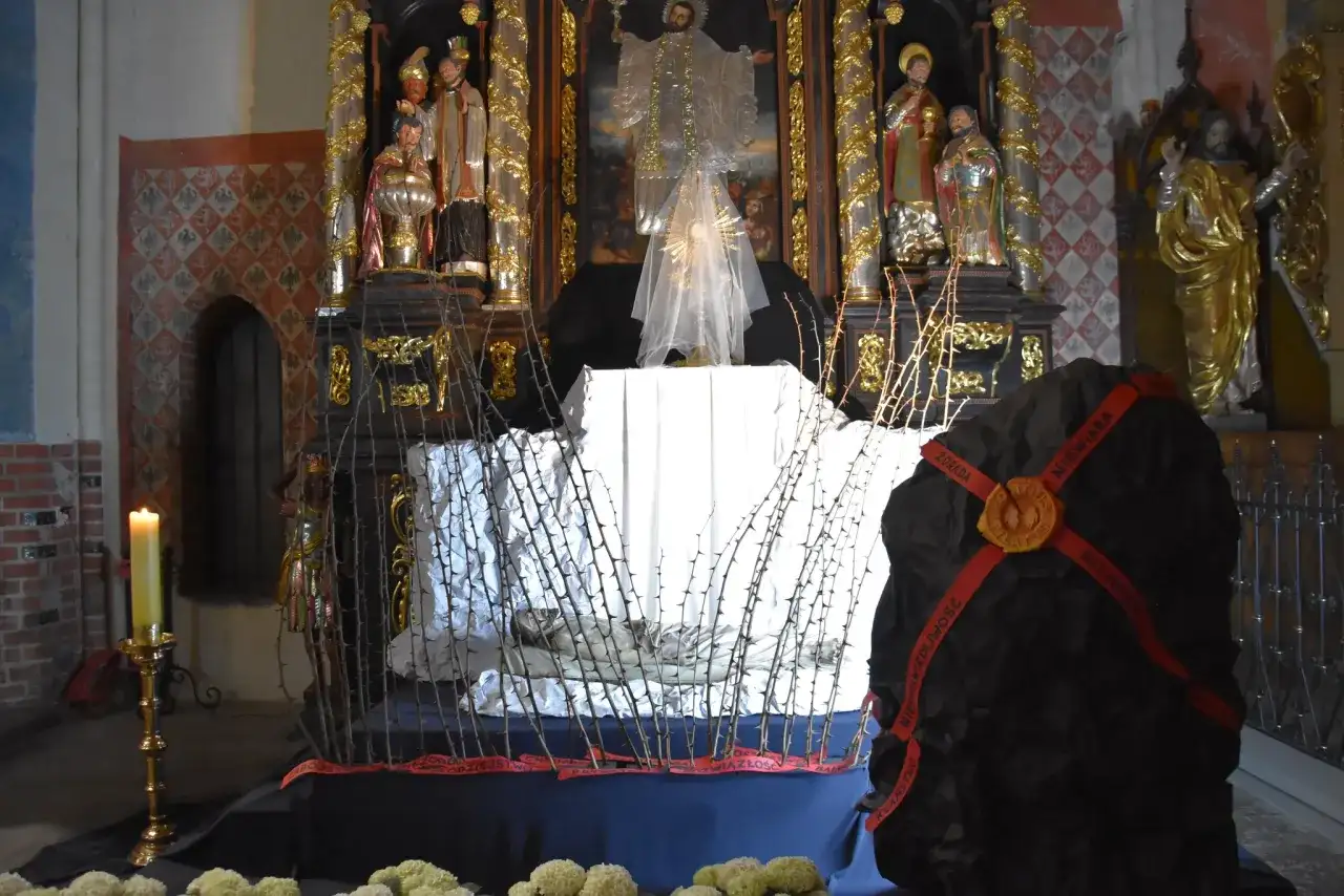 Ołtarz w kościele z grobem Chrystusa, ozdobiony ciernistymi gałęziami i świecą.