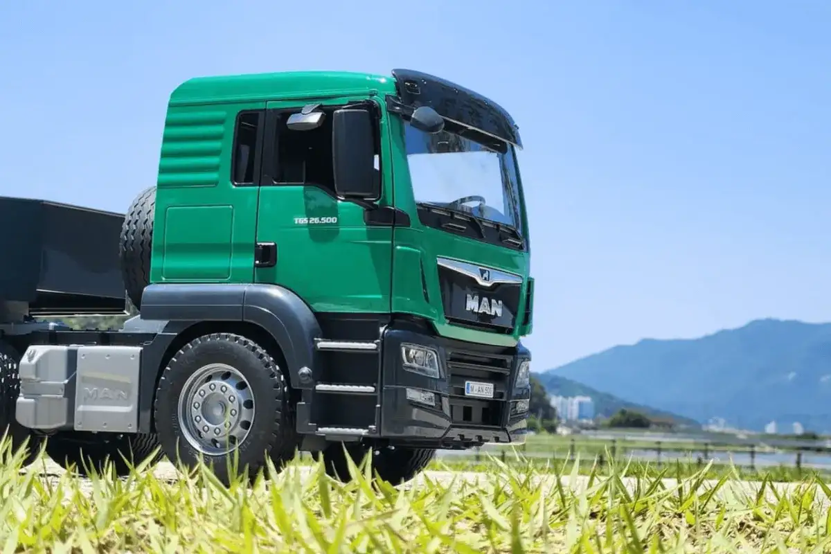 Zielona ciężarówka MAN TGS 26.500 na tle nieba i gór. Zastanawiasz się, ile zarabiają kierowcy tirów?