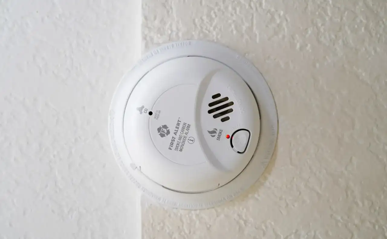 Biały czujnik czadu i dymu na suficie. To urządzenie jest kluczowe, gdy potrzebny jest czujnik czadu, zapewniając bezpieczeństwo.