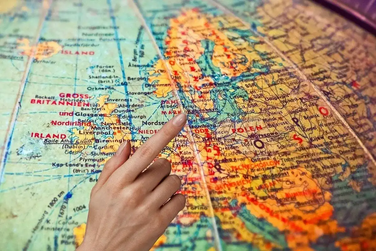 Dłoń wskazująca palcem na mapę Europy, z zaznaczonymi Wielką Brytanią i Polską.