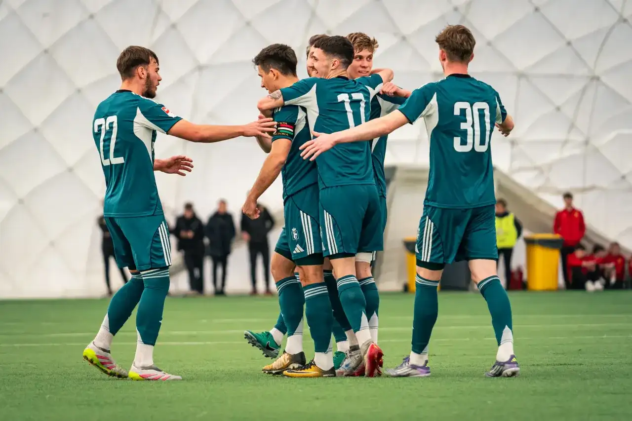 Legia Warszawa zawodnicy w zielonych strojach świętują na boisku.