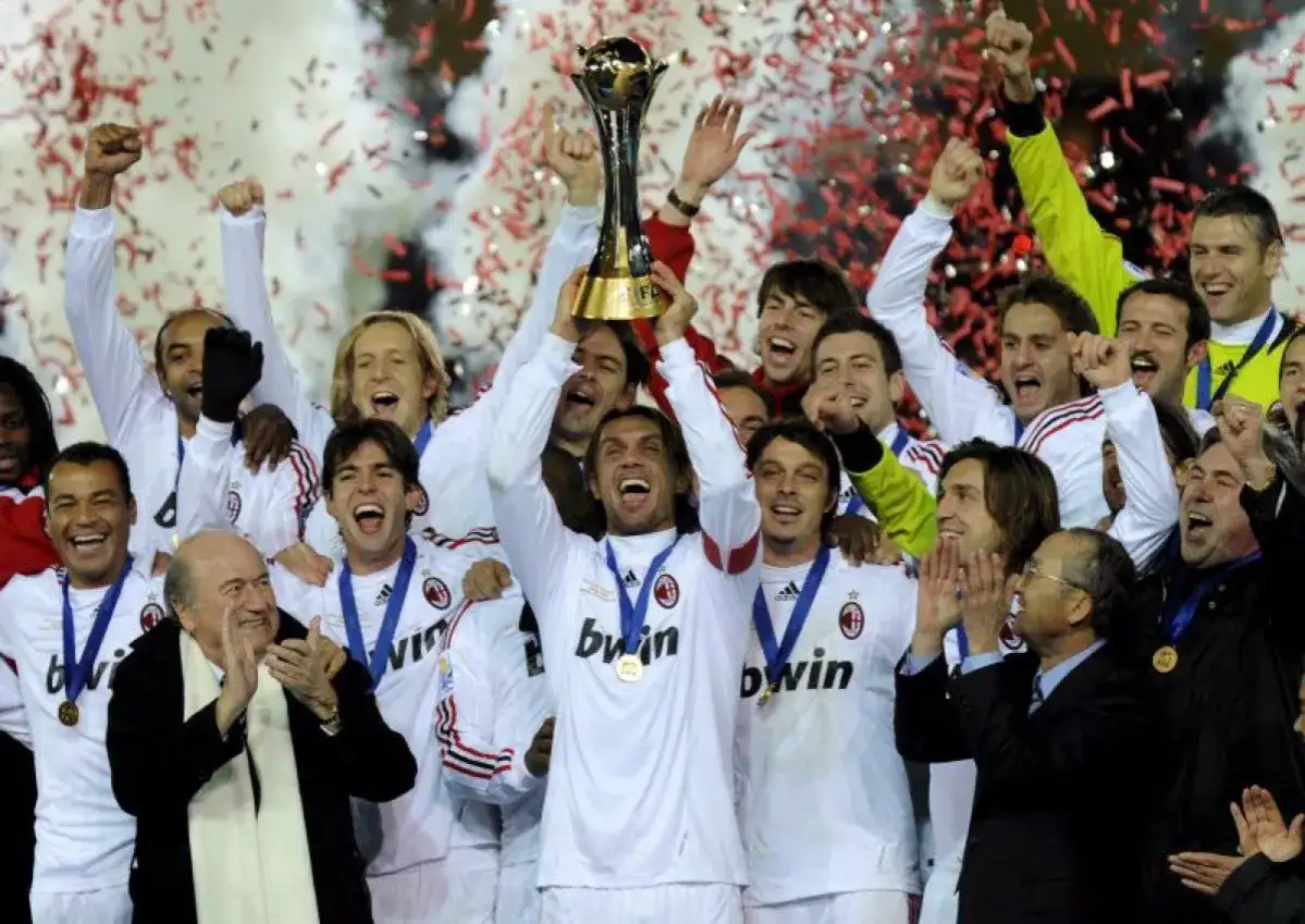 Piłkarze AC Milan świętują z pucharem, w tle konfetti i dym.