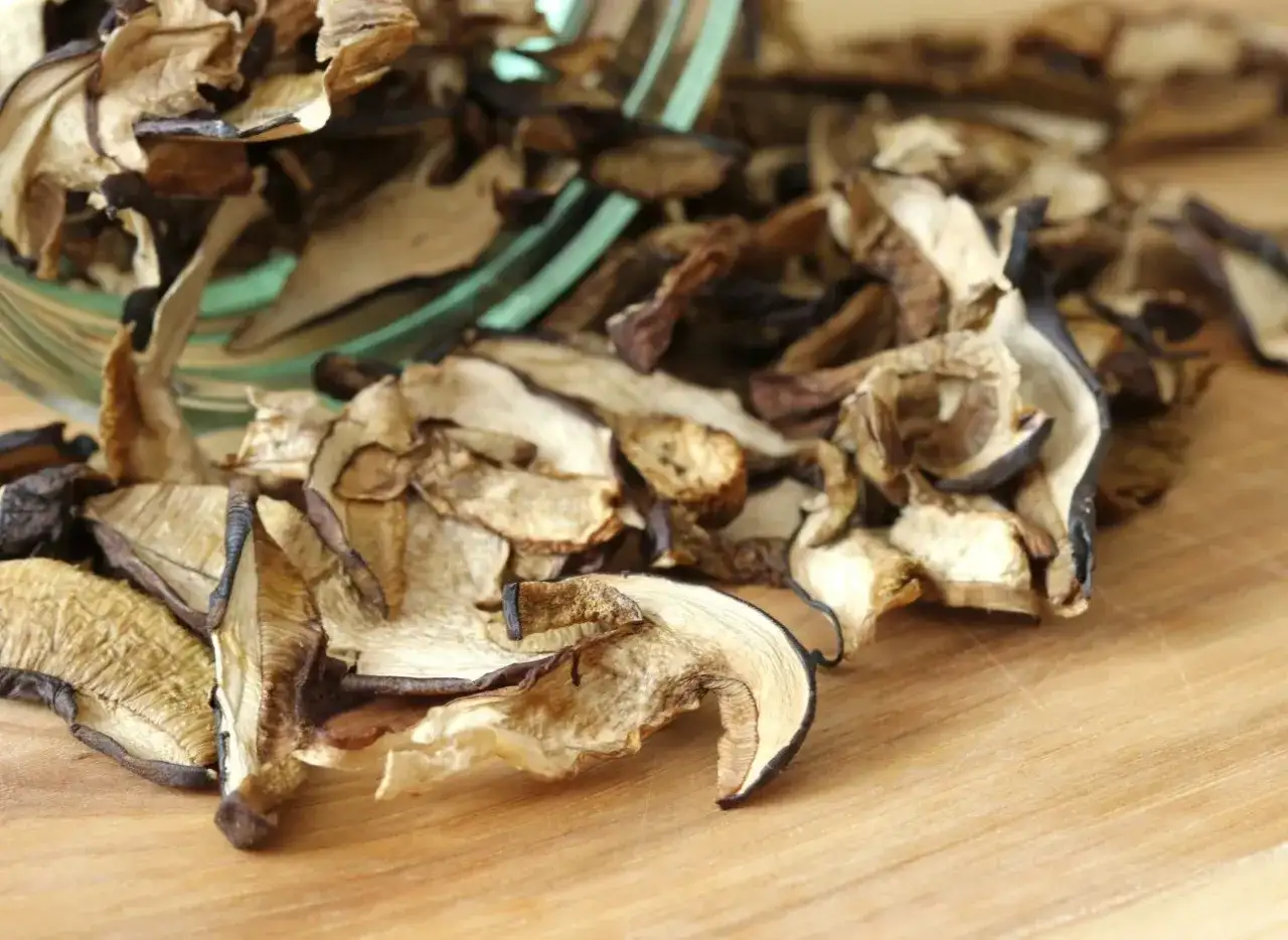 Suszone grzyby na desce. Zastanawiasz się, jak długo gotować suszone grzyby, by były idealne? Oto one, gotowe do namoczenia.