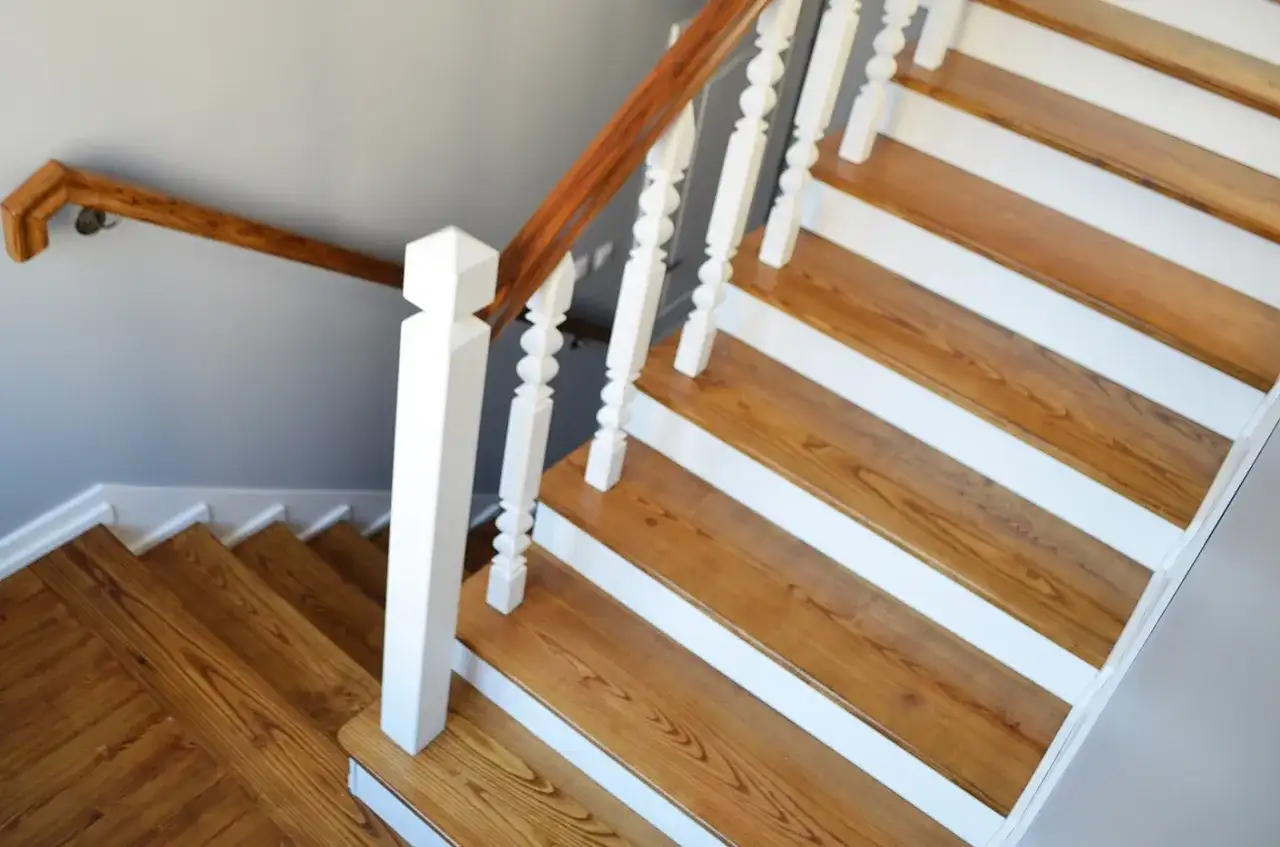 Jak zrobić schody drewniane? Piękne, jasne stopnie z drewnianymi podstopnicami i białymi elementami.