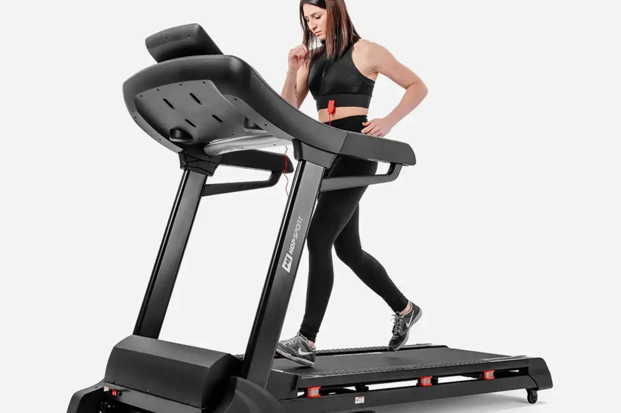 Kobieta w czarnym stroju ćwiczy na bieżni.