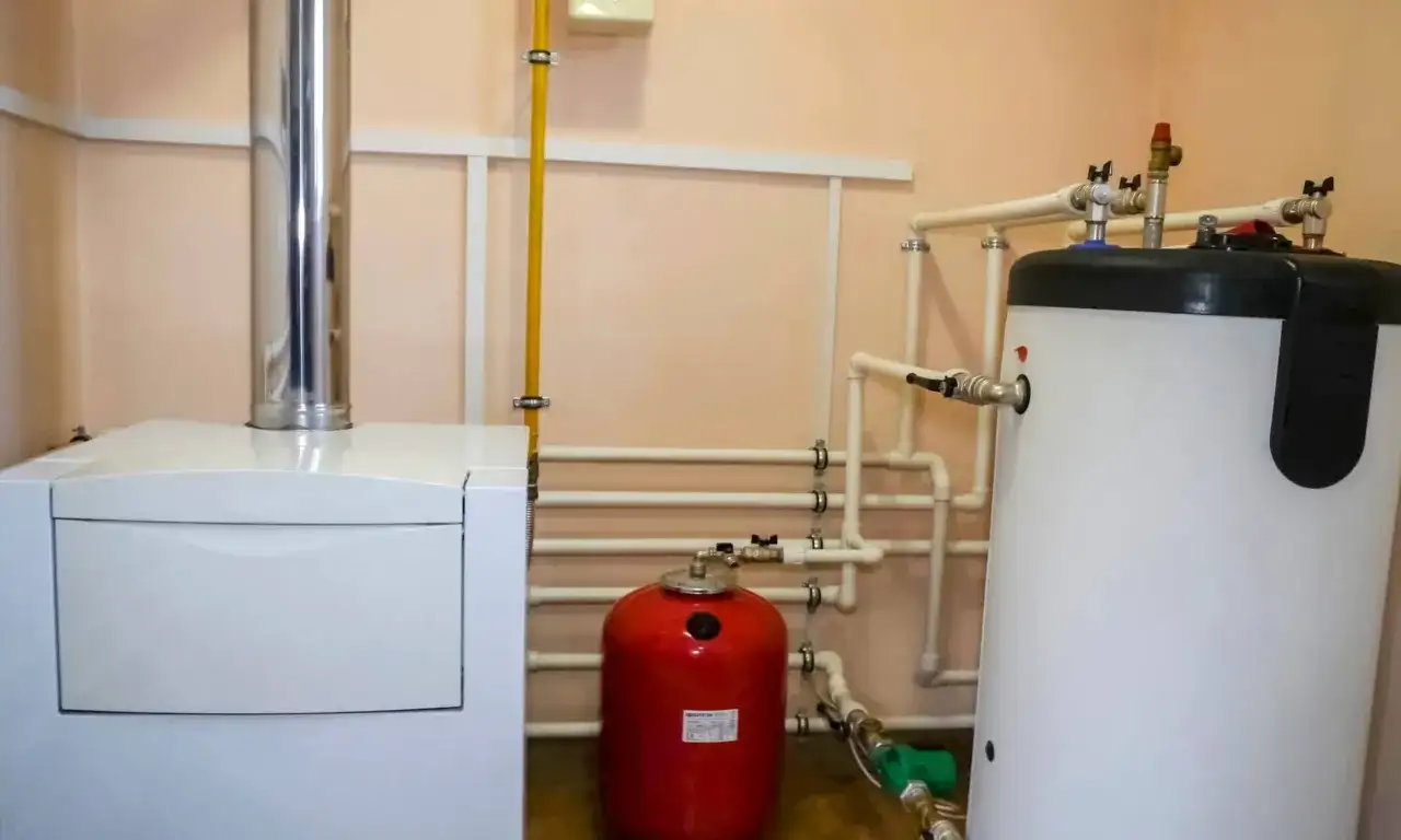 Caldera blanca, depósito rojo y calentador de agua blanco con tuberías.