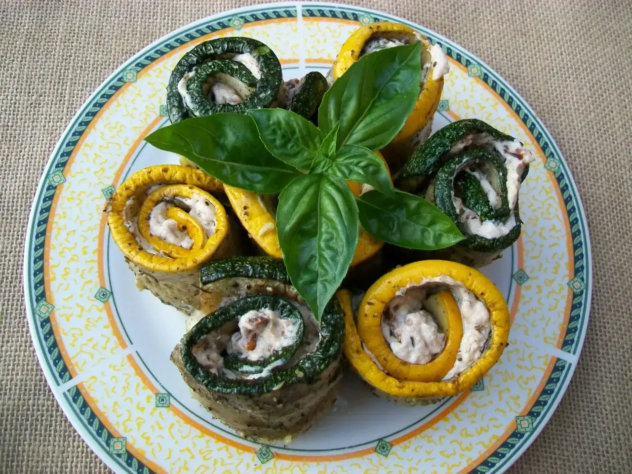 Roladki z cukinii i żółtej dyni faszerowane kremowym farszem, ozdobione gałązką bazylii. Idealne jako przystawka, do czego jeszcze?