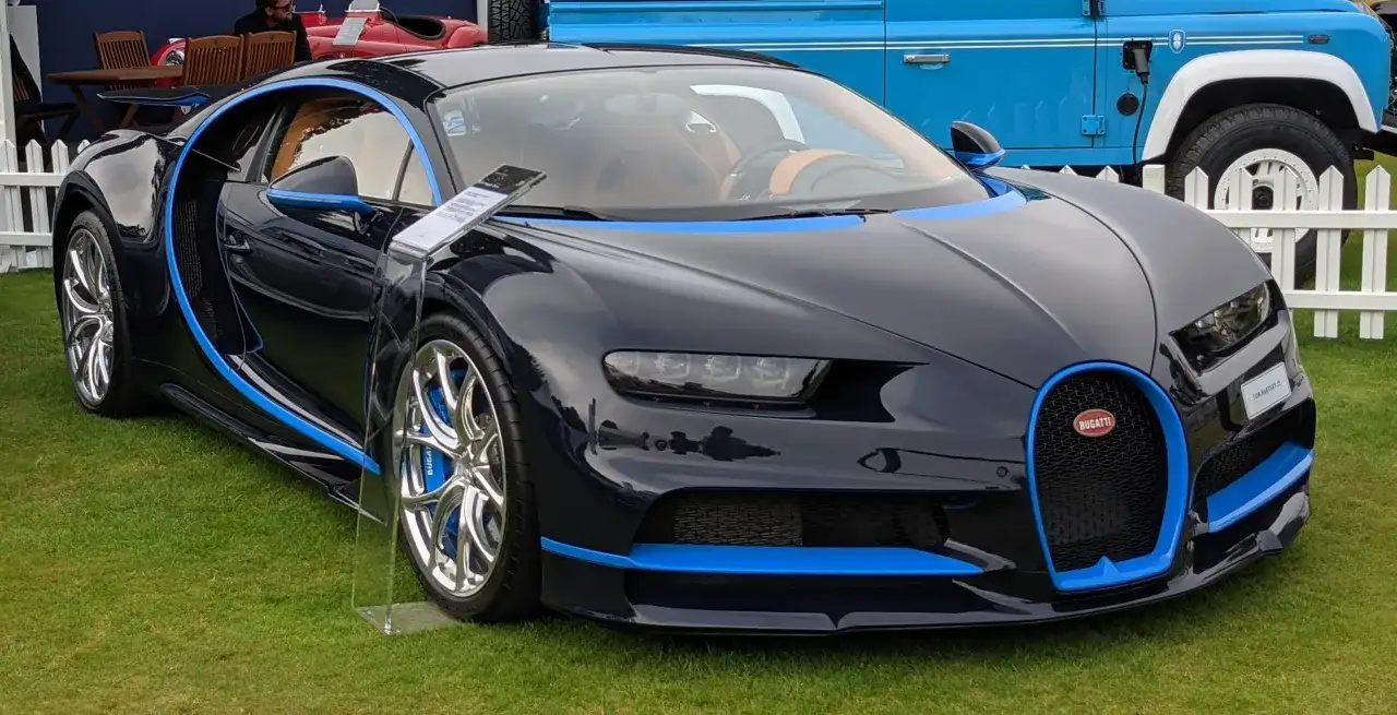 Ciemnoniebieskie Bugatti Chiron z niebieskimi akcentami na trawie.