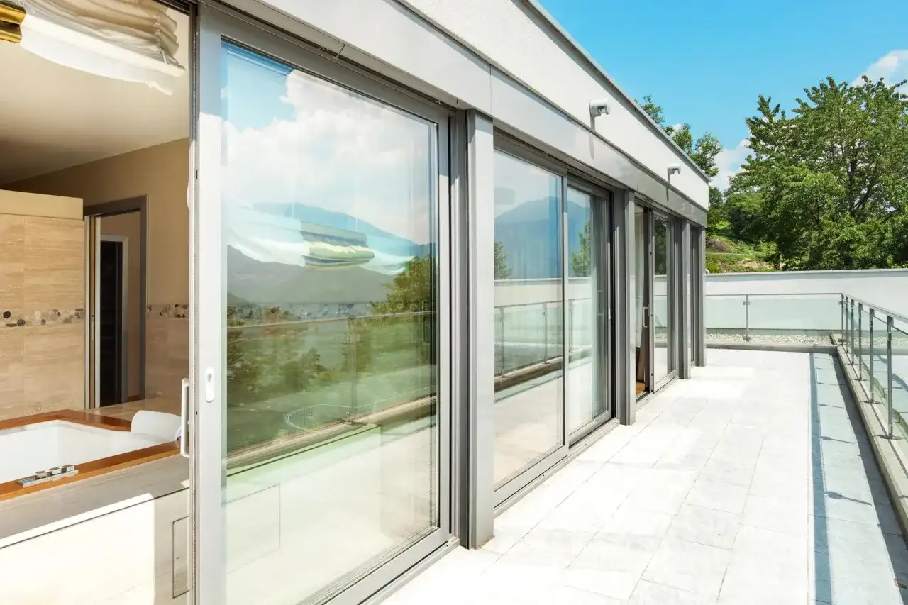 Nowoczesny balkon z przeszklonymi drzwiami i widokiem na góry.