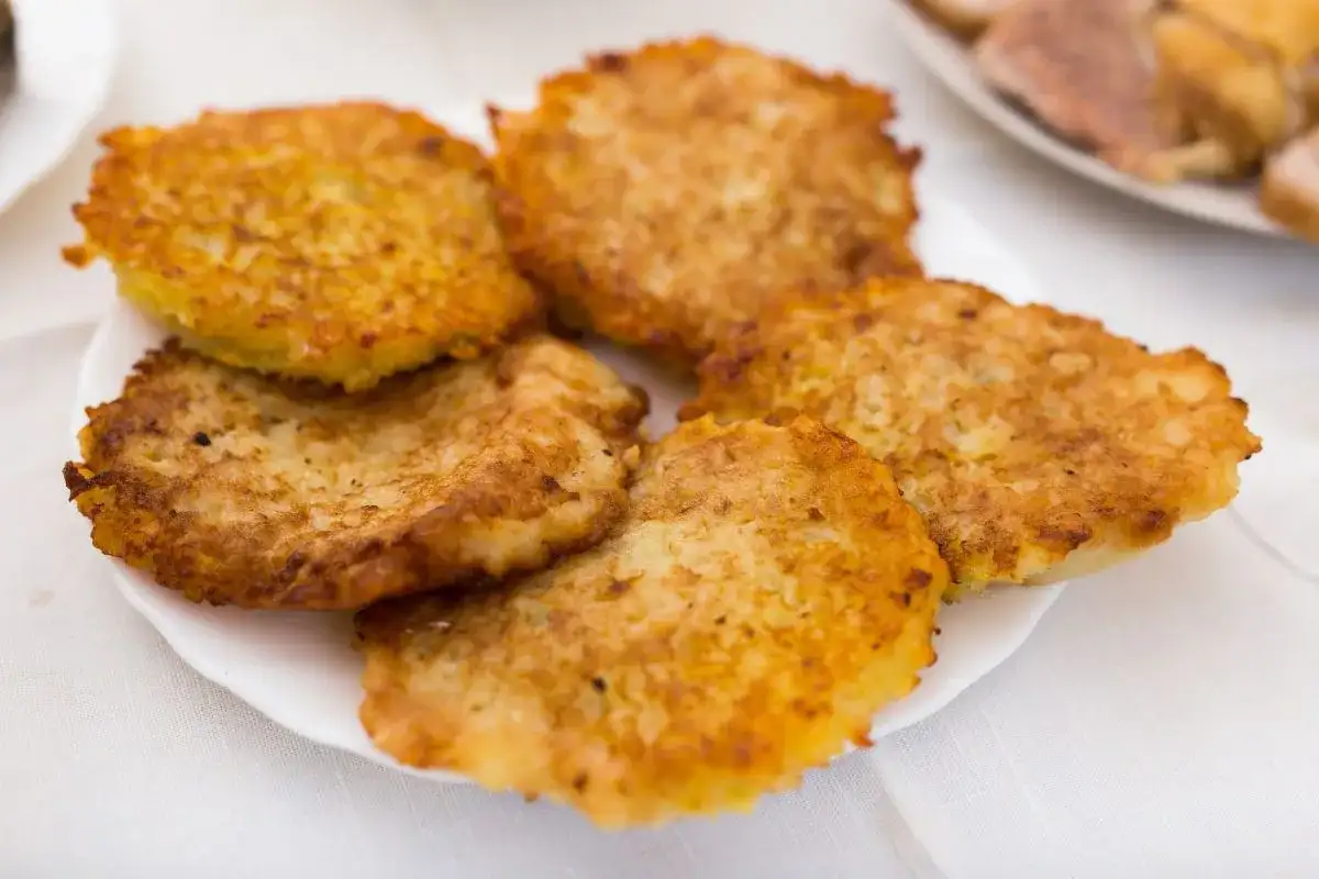 Placki ziemniaczane na białym talerzu, lekko zrumienione.