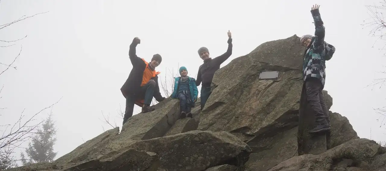 Rodzina zdobyła skopiec szczyt. Radosne okrzyki na skale w mglisty dzień.