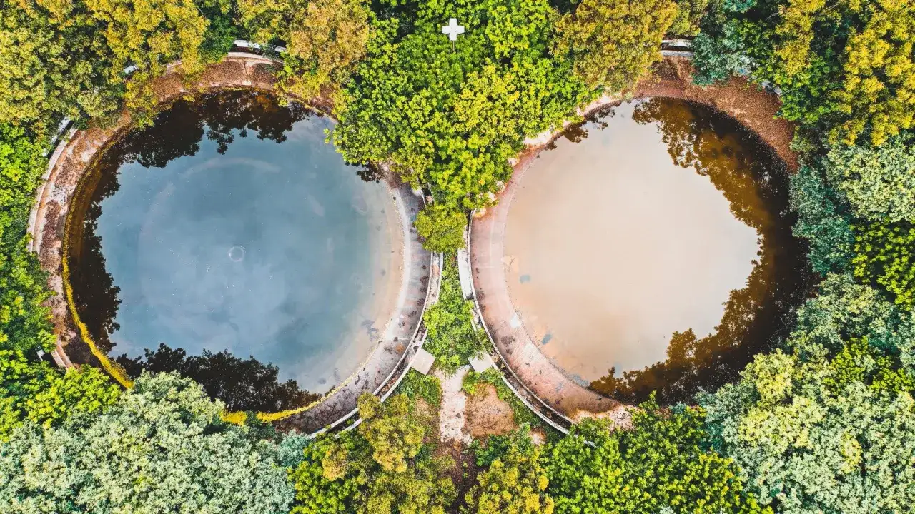 Dwa okrągłe zbiorniki oczyszczalni ścieków otoczone zielenią. Zastanawiasz się, jak pozbyć się brzydkiego zapachu z oczyszczalni ścieków?