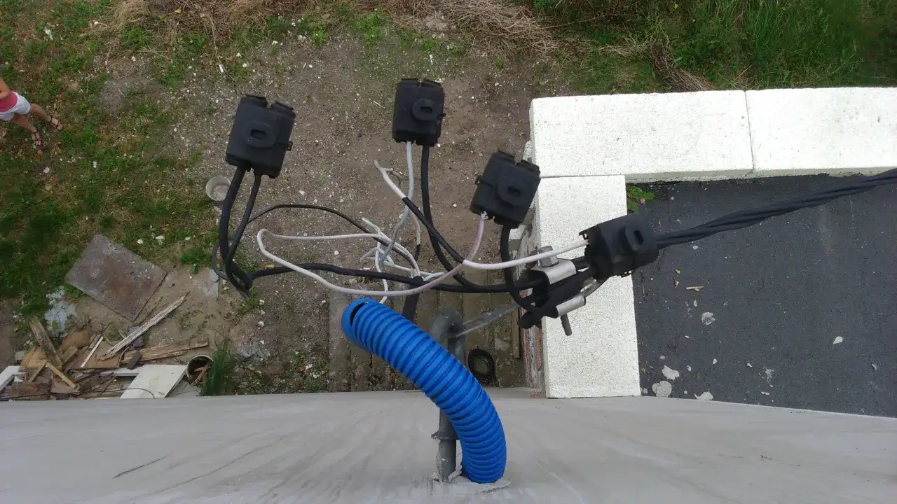 Widoczne połączenia kablowe, w tym niebieska peszla, wskazują na instalację elektryczną. To może być właśnie taki kabel od licznika do rozdzielni.