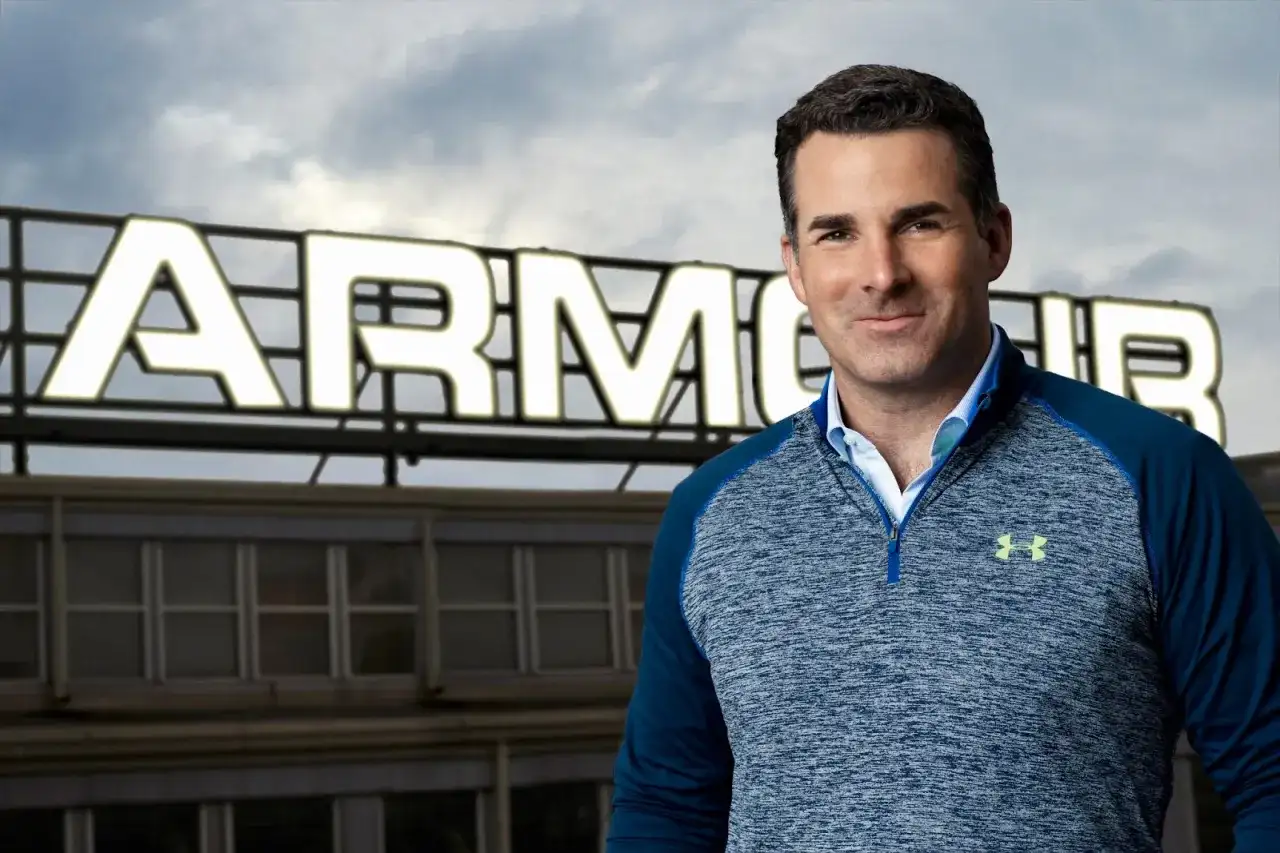 Mężczyzna w bluzie Under Armour na tle budynku z napisem ARMOUR.