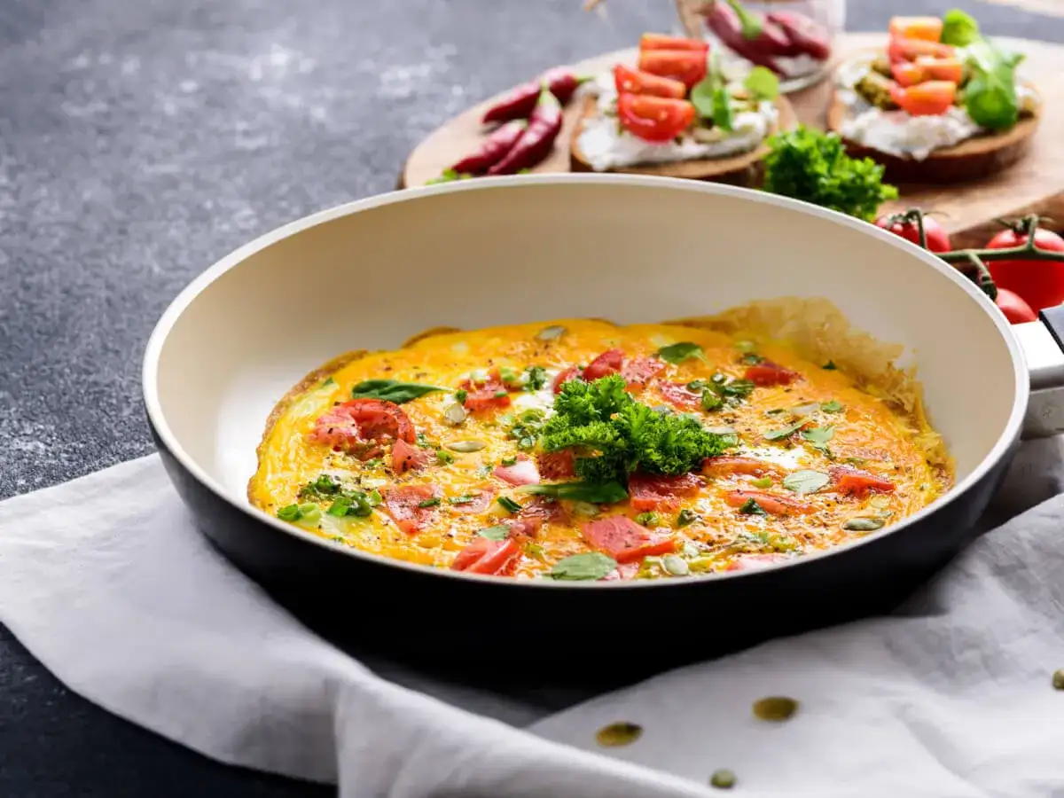 Omlet z pomidorami i ziołami na patelni. Idealny sposób, jak ograniczyć węglowodany w diecie.