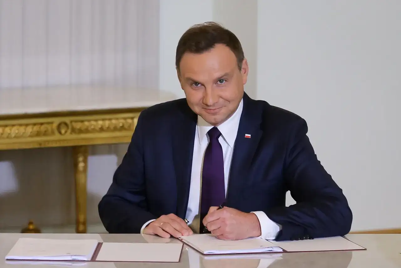 Prezydent Duda w garniturze podpisuje dokument. Ile lat ma Duda? To pytanie, na które odpowiedź znajdziemy w jego biografii.