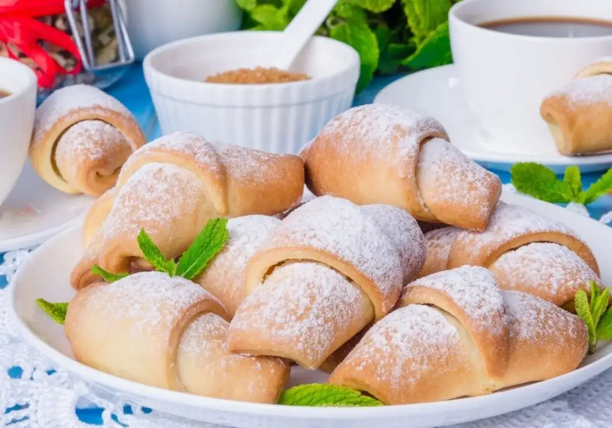 Pyszne, kruche rogaliki posypane cukrem pudrem, udekorowane listkami mięty. Idealne na deser lub do kawy.