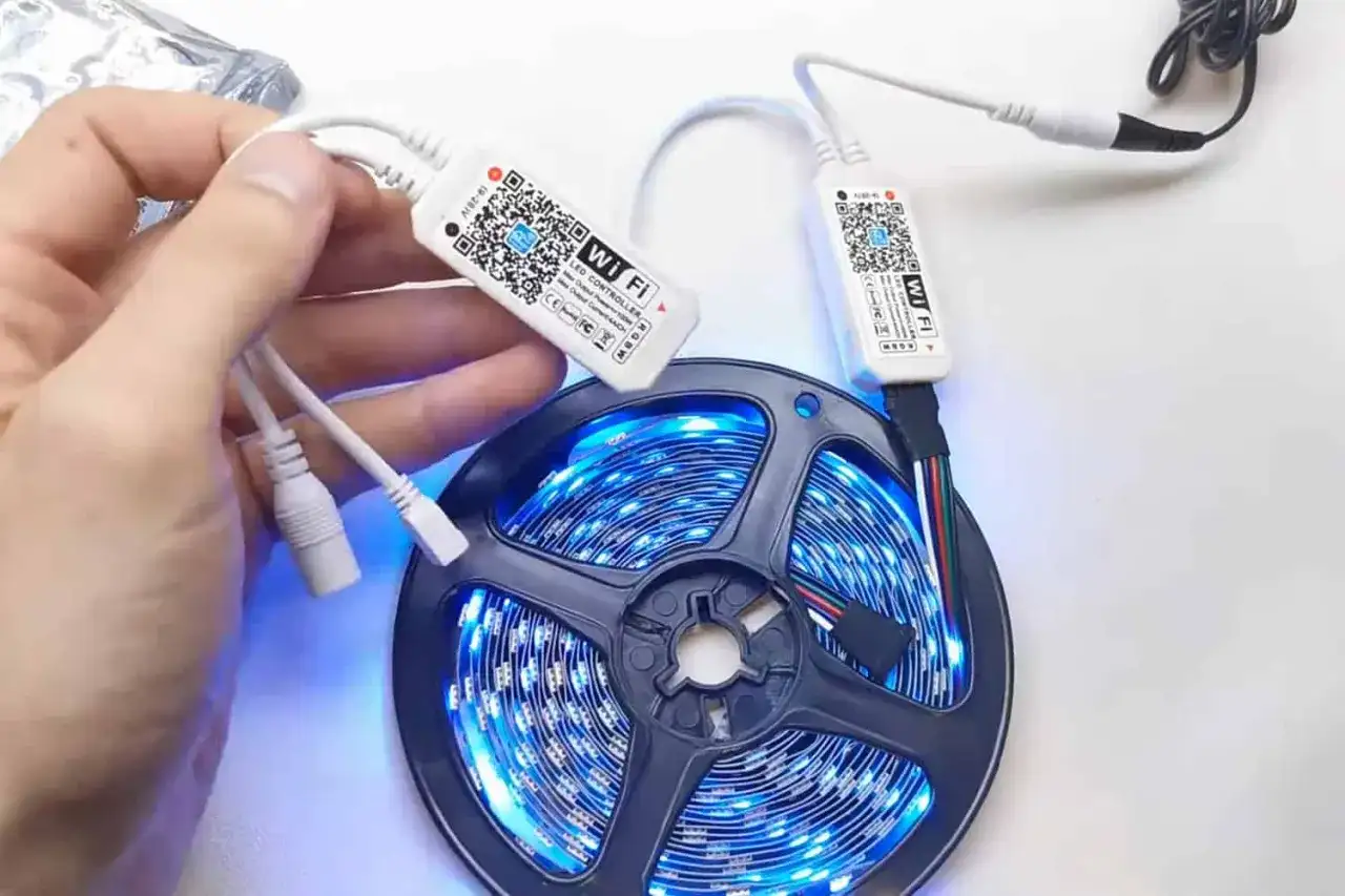 Ręka trzymająca kontroler Wi-Fi do taśmy LED. Dowiedz się, jak zresetować pilot do ledów, skanując kod QR.