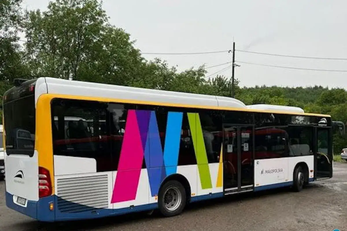 Autobus z kolorowym logo i napisem "Małopolska" na tle drzew.