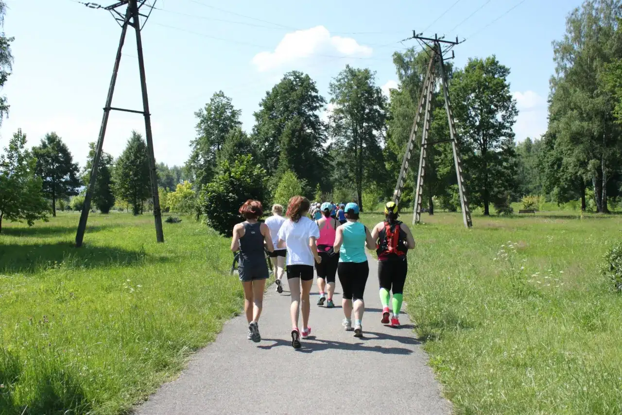 Grupa kobiet biegnie ścieżką w parku, uczestnicząc w obozach bieganie.