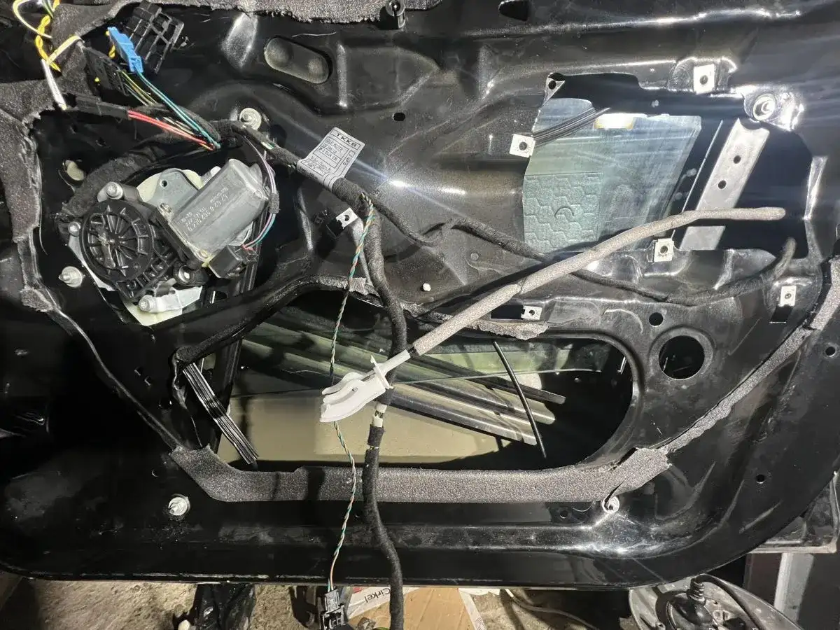 Wnętrze drzwi BMW E46 z widocznym mechanizmem podnoszenia szyby i przewodami.