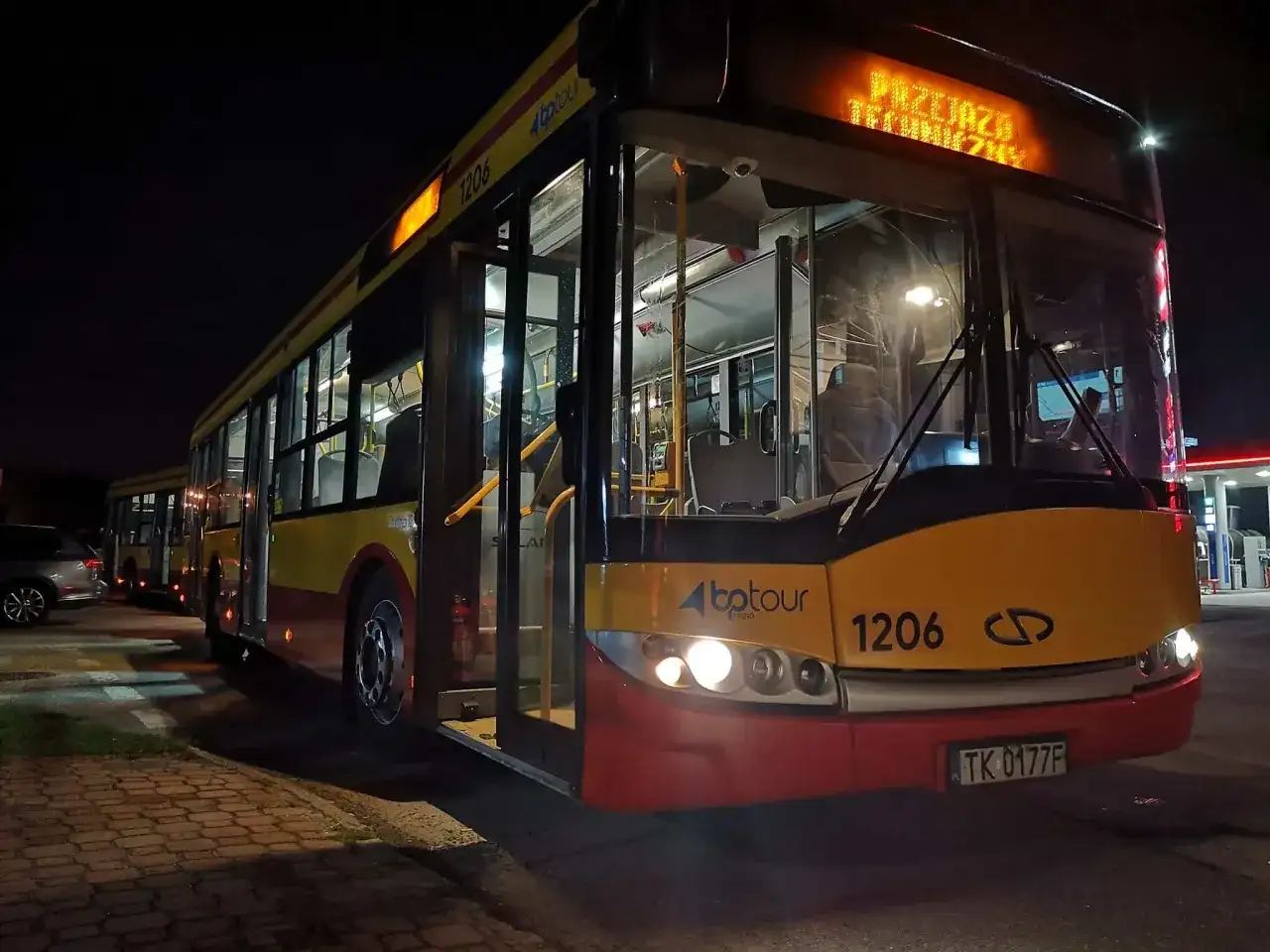 Autobus BP Tour z numerem 1206 na nocnym postoju, z zapalonymi światłami.