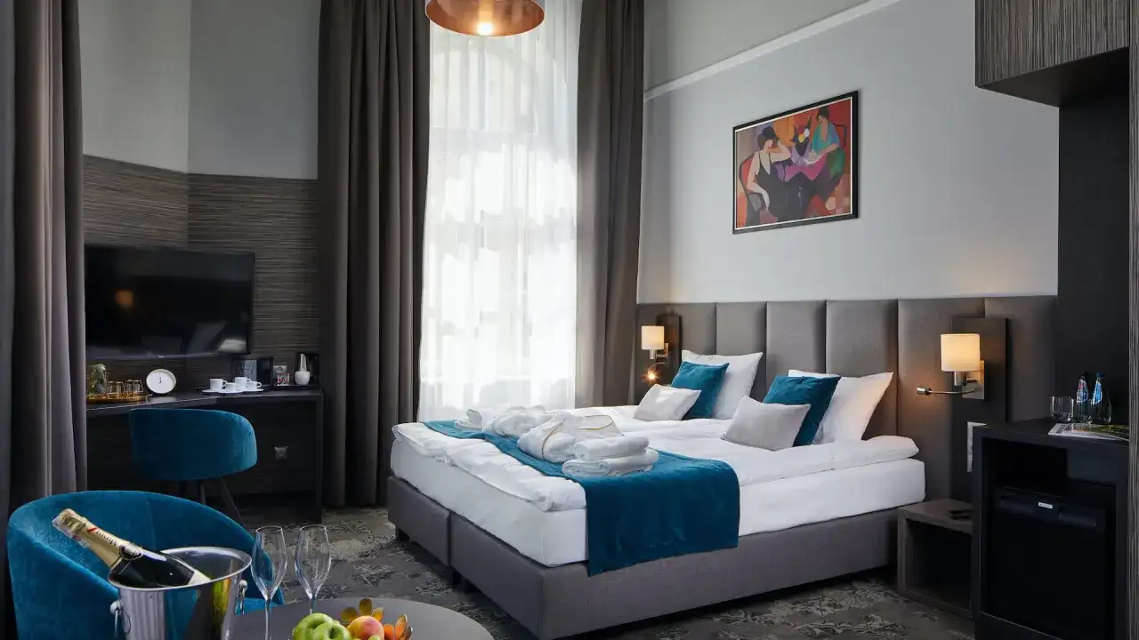 Elegancki pokój hotelowy w Krakowie z wygodnym łóżkiem, szlafrokami i butelką szampana. Sprawdź, ile kosztuje nocleg w Krakowie!