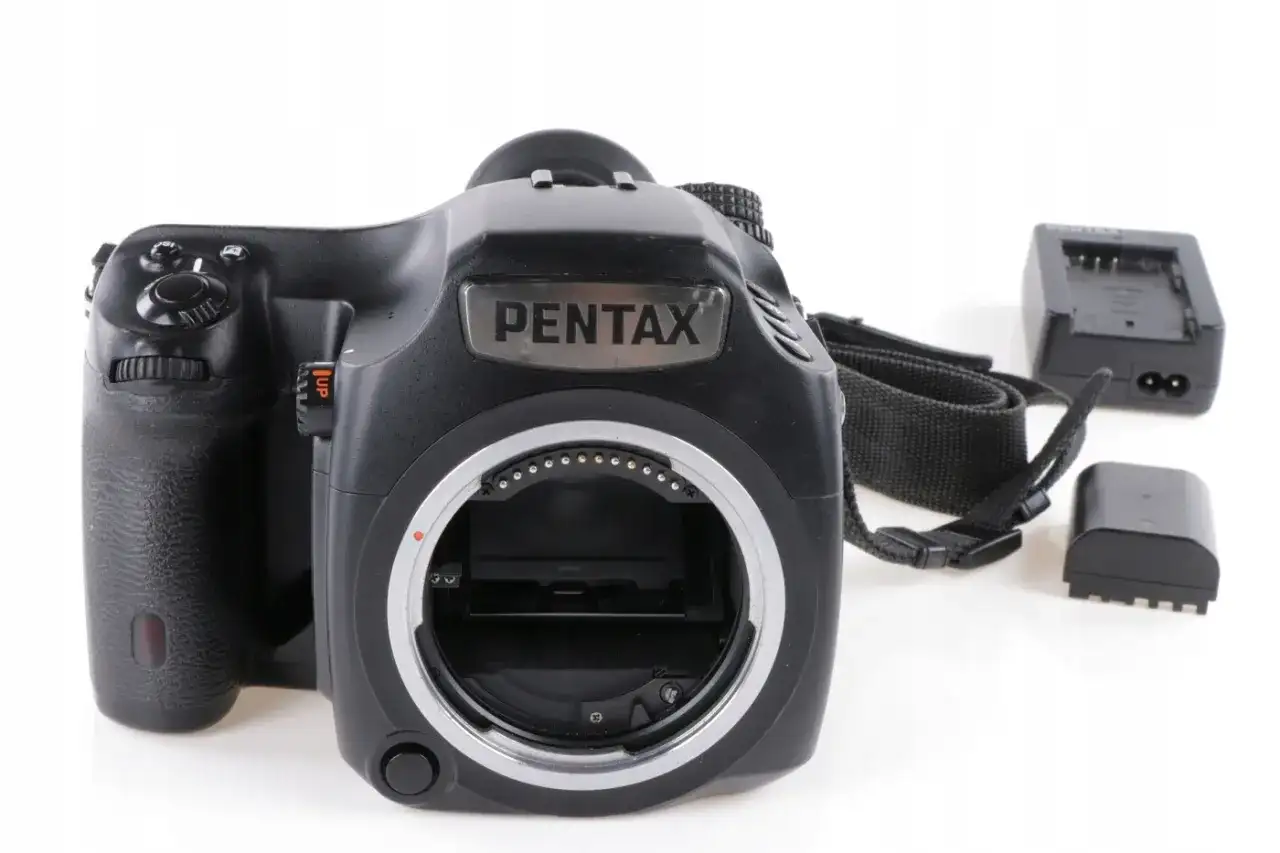 Czarna lustrzanka cyfrowa Pentax z paskiem i akcesoriami, gotowa do aukcji na Allegro.