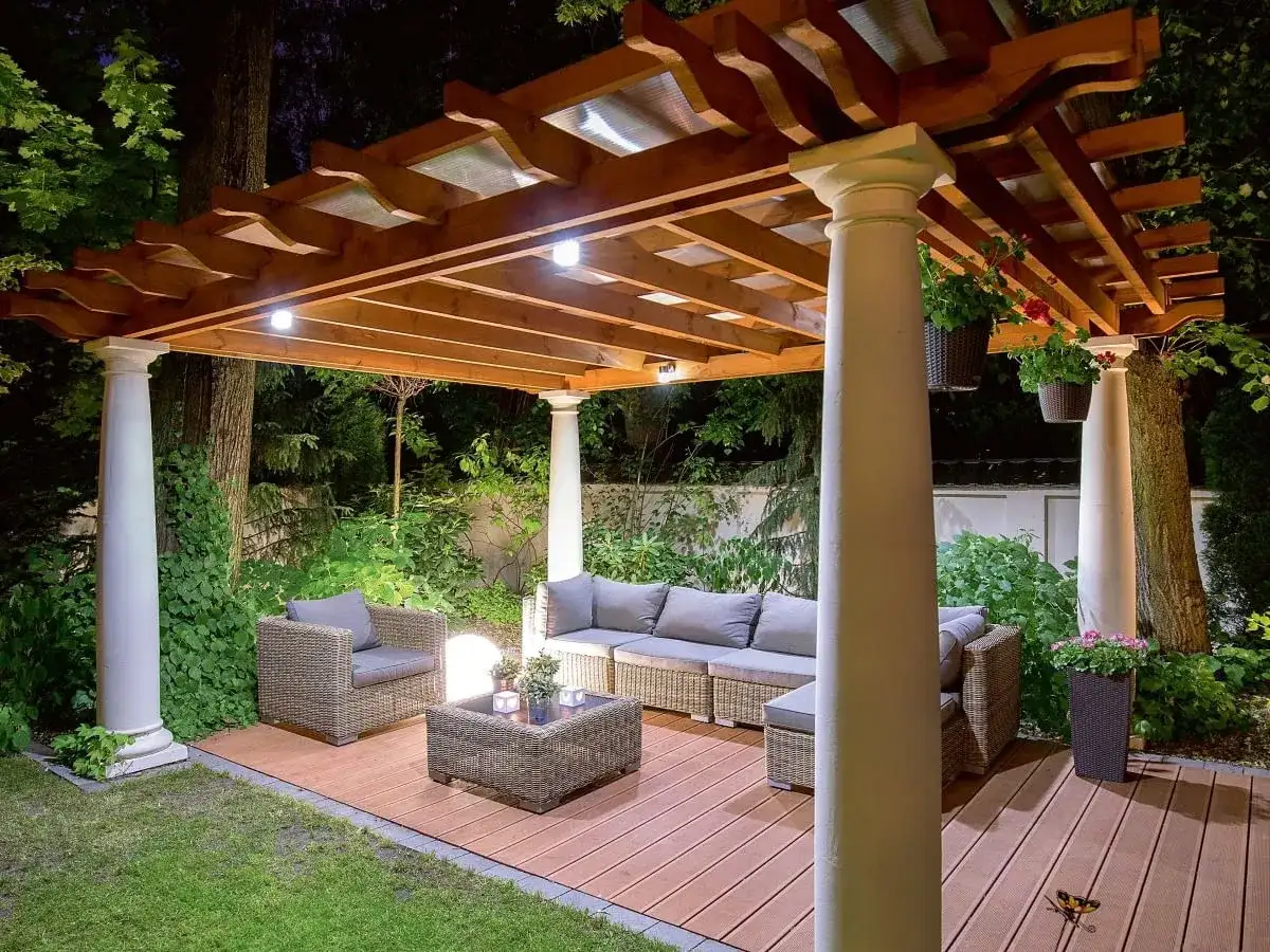 Drewniane tarasy na słupach z zadaszeniem tworzą przytulne miejsce wypoczynku. Wygodne meble i oświetlenie zachęcają do relaksu.