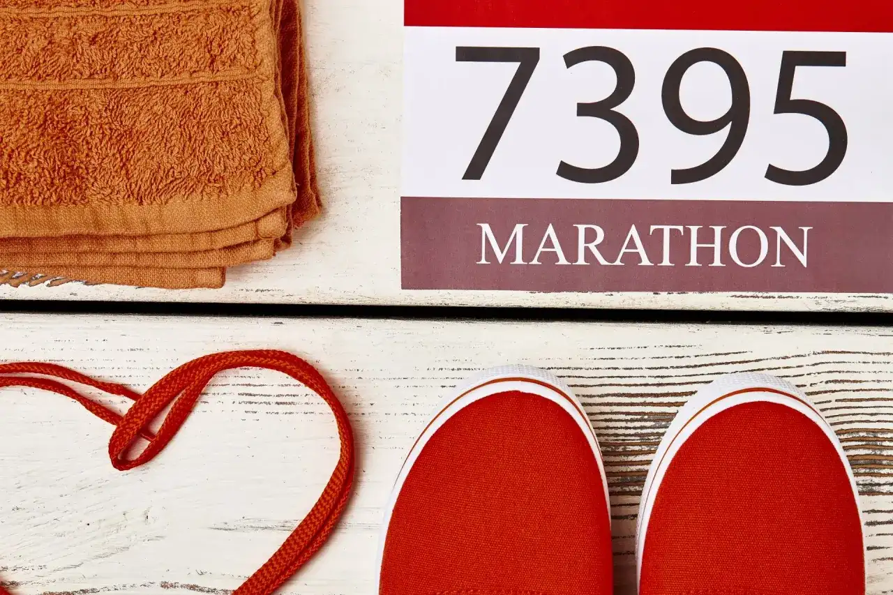 Pomarańczowy ręcznik, czerwone buty i numer startowy 7395. Czy to przygotowania do maratonu, który ma 42,195 km?