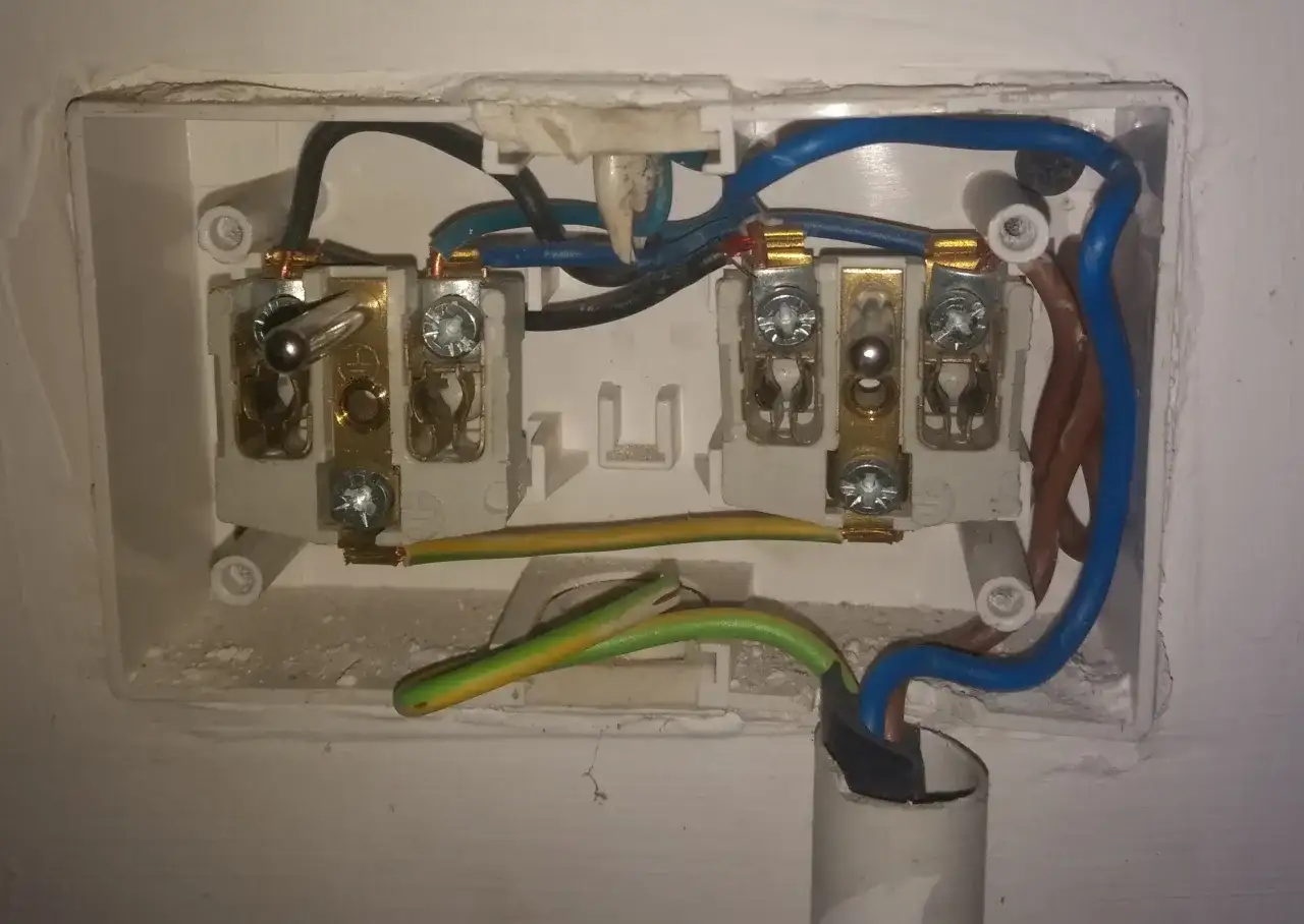 Podłączenie kabla siłowego 4 żyłowego: przewody niebieski, brązowy, czarny i żółto-zielony wchodzą do białej puszki instalacyjnej.