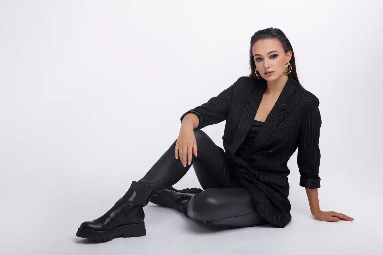 Elegancka kobieta w czarnym garniturze i spodniach woskowanych, prezentująca stylowe, nowoczesne stylizacje.