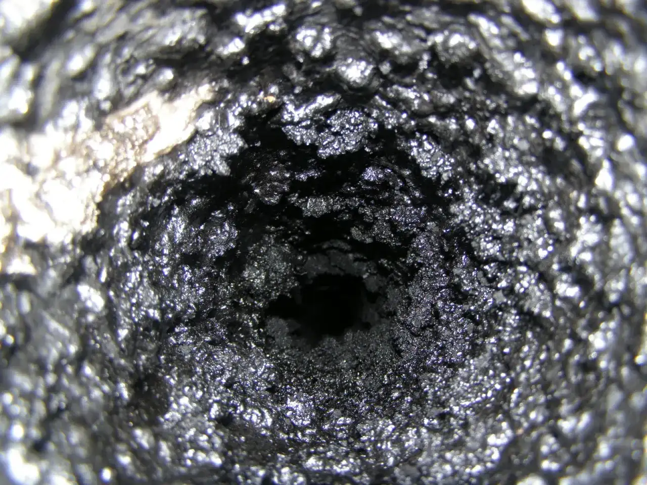 Zatkany komin z grubą warstwą sadzy. Dowiedz się, jak usunąć smołę z pieca i komina, by zapewnić bezpieczeństwo.