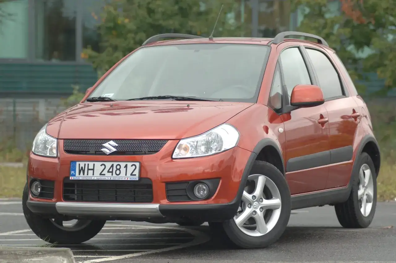 Pomarańczowy Suzuki SX4 z przodu, z widoczną tablicą rejestracyjną.