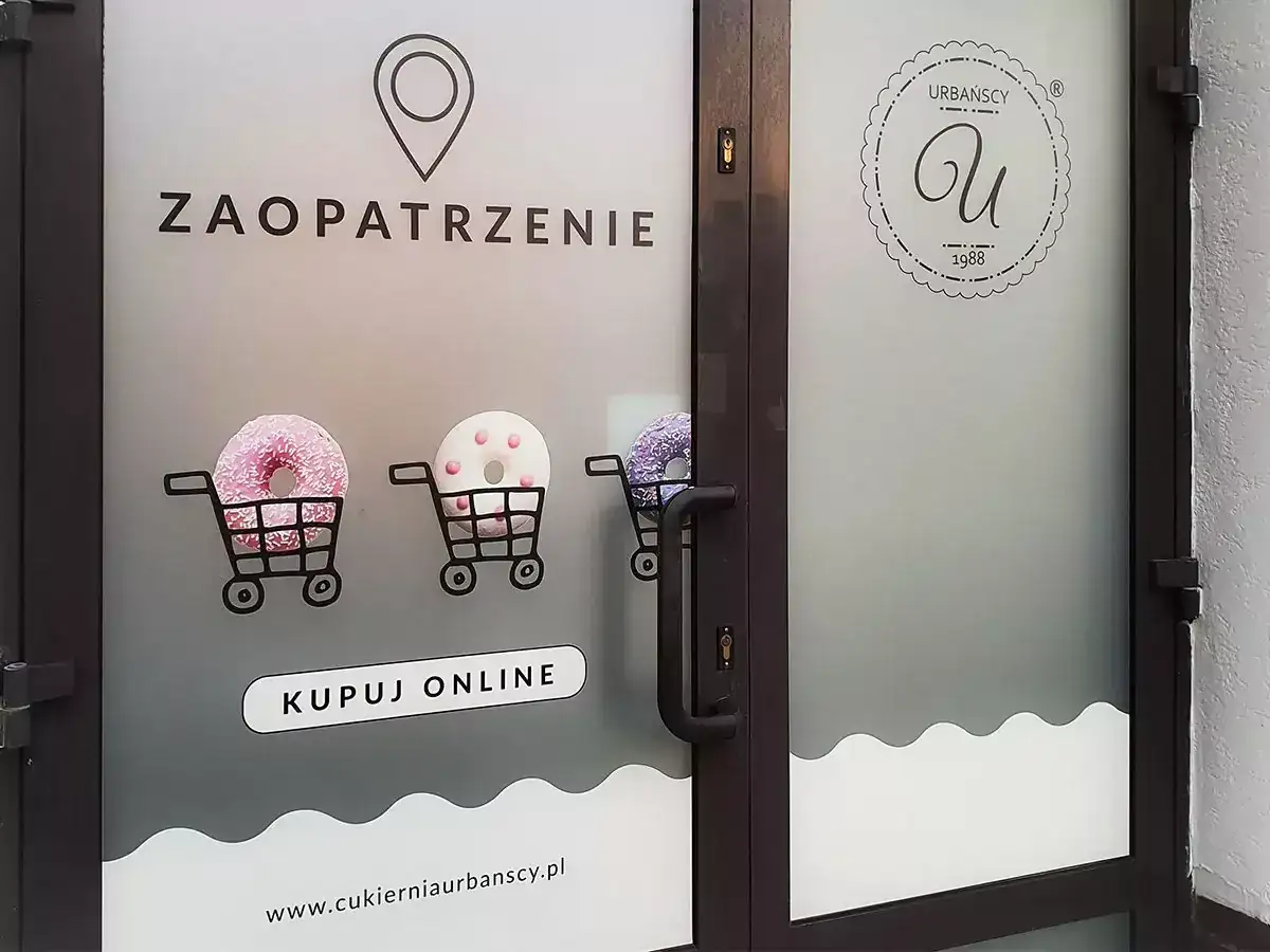 Drzwi z folią z napisem "ZAOPATRZENIE", wózkami z pączkami i logo cukierni.