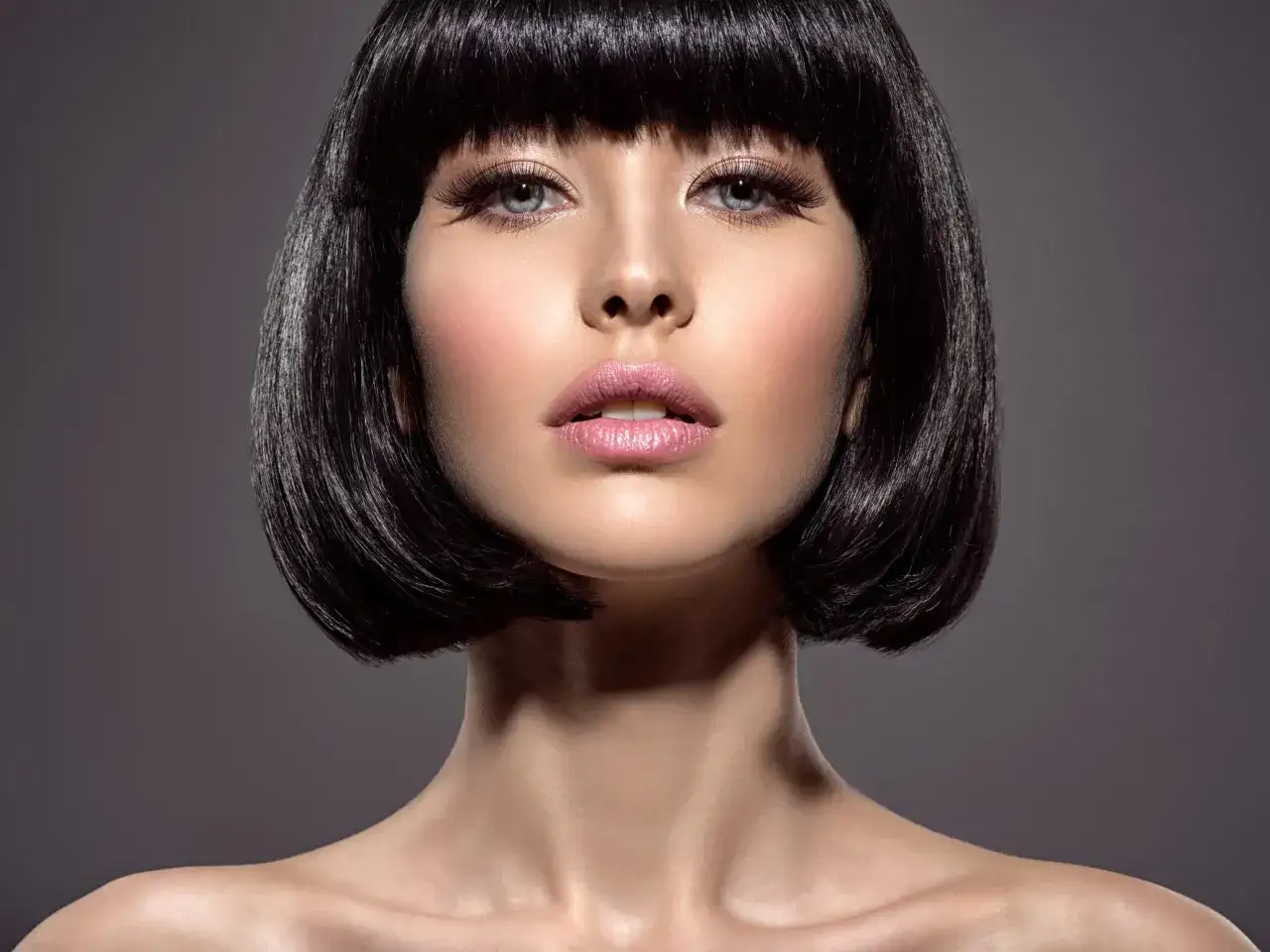 Portret kobiety z krótkimi, czarnymi włosami i makijażem.