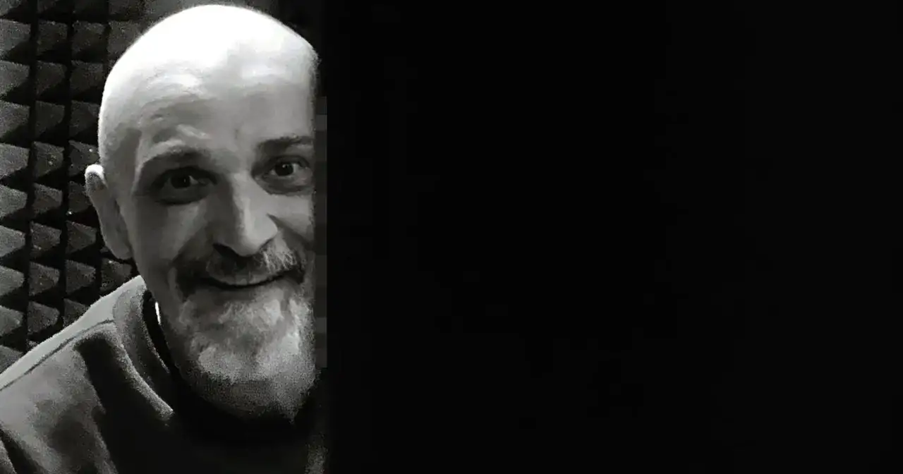 Uśmiechnięty Wojciech Sęp Dudziński, z charakterystyczną brodą i łysą głową, w studiu nagraniowym.