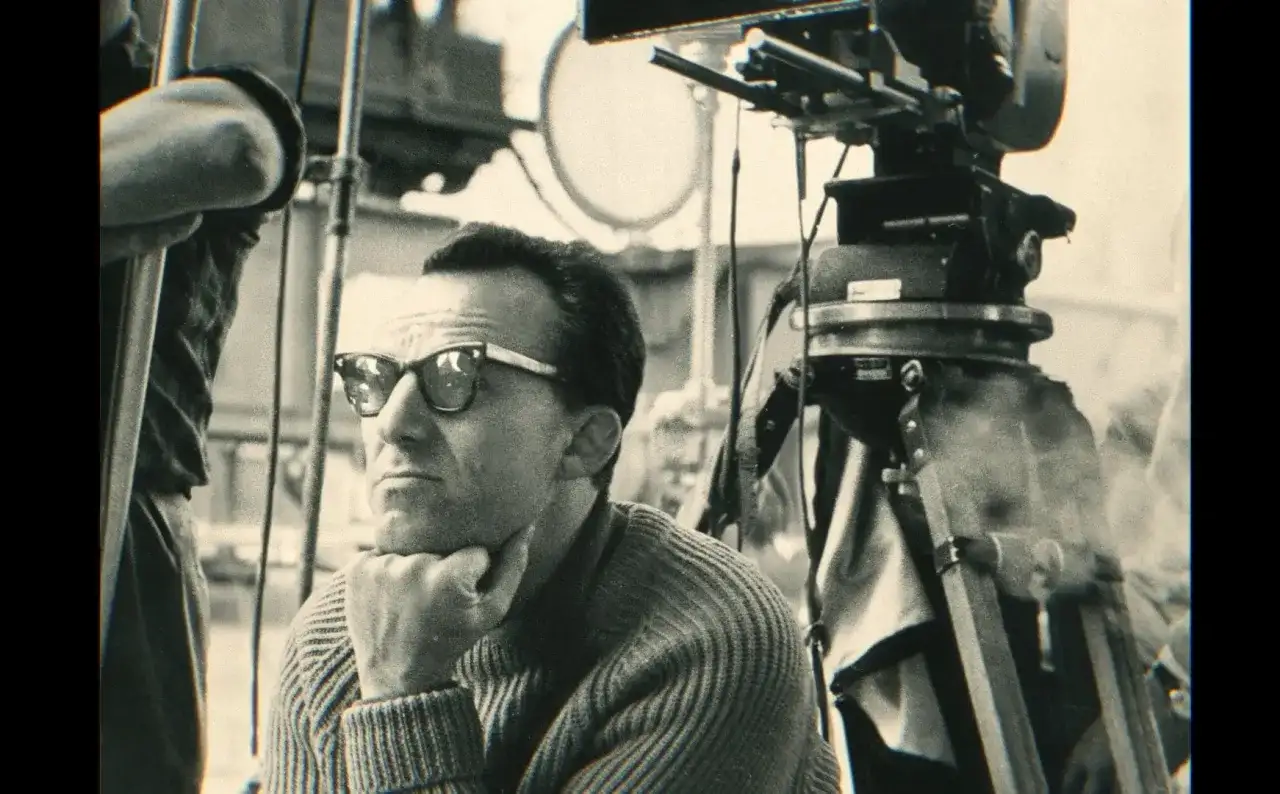 Reżyser "Zezowatego szczęścia" w okularach, zamyślony, na planie filmowym obok kamery.