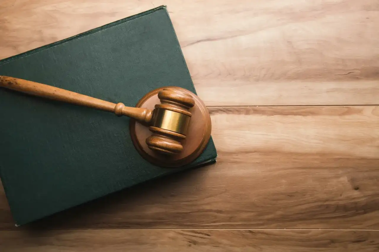 Młotek sędziowski na zielonej księdze. Zastanawiasz się, ile się czeka na rozprawę sądową?